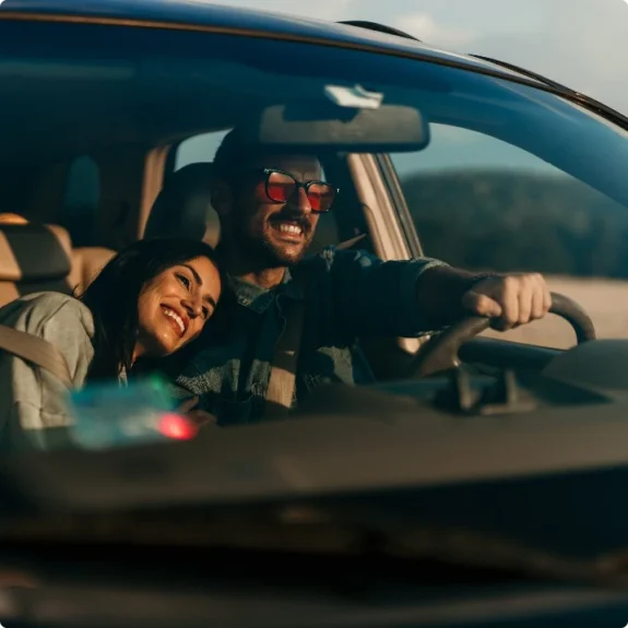 Leende par kör bil i solnedgång efter service hos Autoexperten Huskvarna.